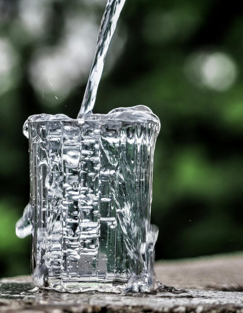 Cold spring water being poured into a clear glass on a kitchen counter