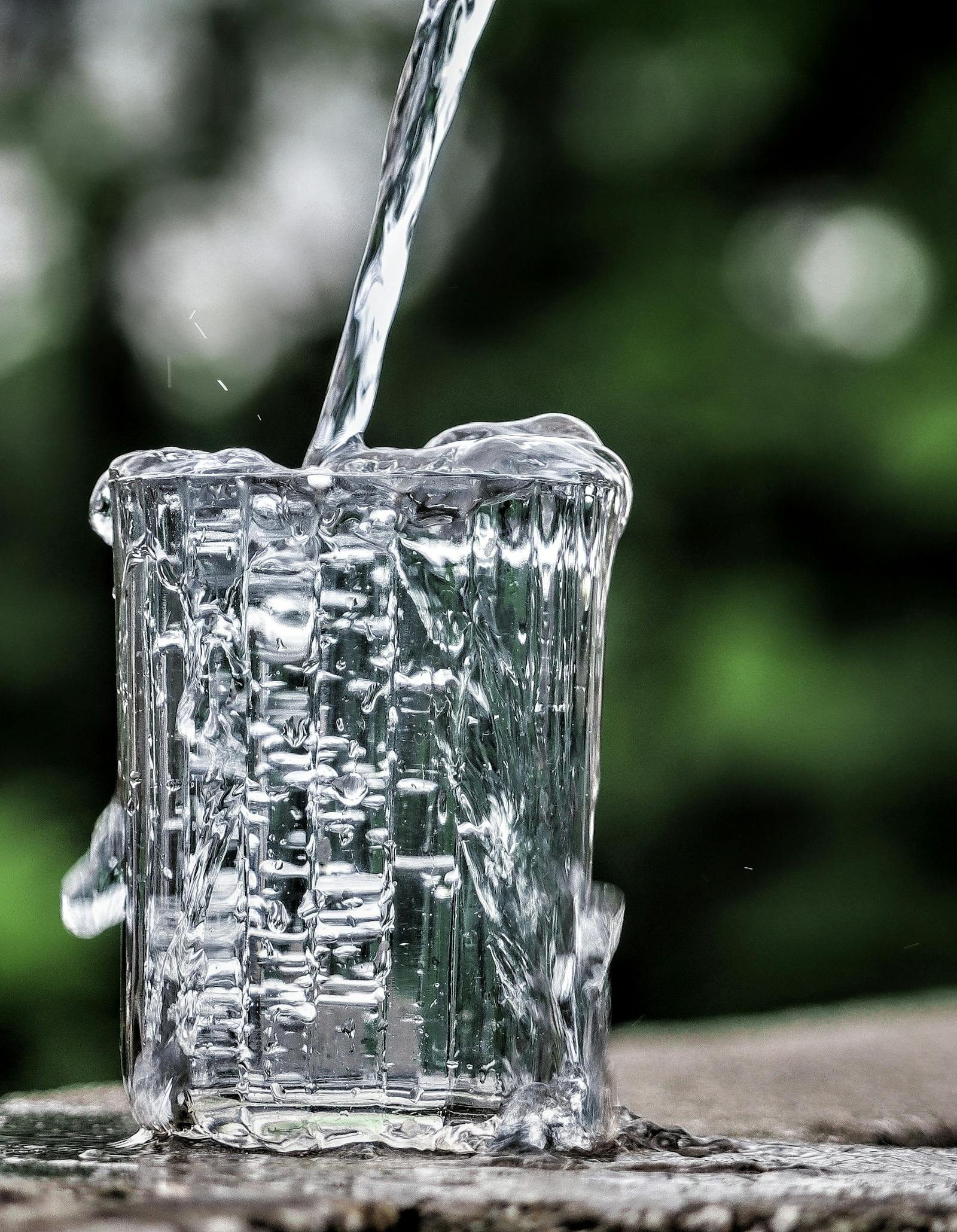 Cold spring water being poured into a clear glass on a kitchen counter